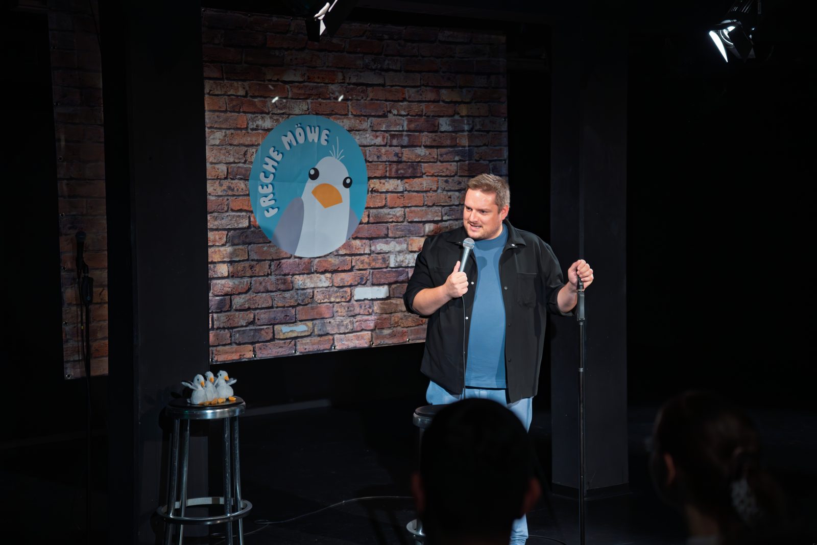 Comedian am Mikrofon vor der Backdrop